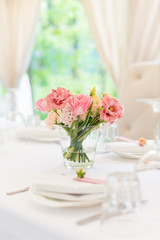 Flower table decorations for holidays and wedding dinner. Table set for holiday, event, party or wedding reception in outdoor restaurant.