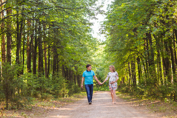 Fototapeta premium happy young pregnant woman with her husband walking in a park
