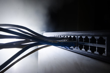 Network switch and ethernet cables, symbol of global communications. Colored network cables on dark...