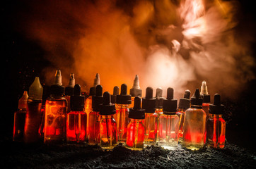Vape concept. Smoke clouds and vape liquid bottles on dark background. Light effects.