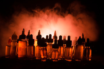 Vape concept. Smoke clouds and vape liquid bottles on dark background. Light effects.