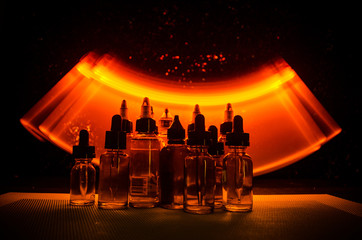 Vape concept. Smoke clouds and vape liquid bottles on dark background. Light effects.