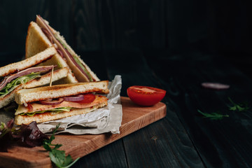 Fresh delicious club sandwich on the wooden dark table with copy space