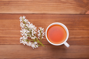 Cup of tea and a bouquet of lilacs on a wooden background.