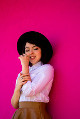 Attractive happy girl in a black hat. Pink Wall