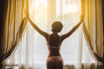 Young woman in lingerie standing at the window