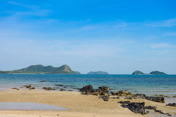 Fototapeta na wymiar Rock on the beach with blue sky and island background