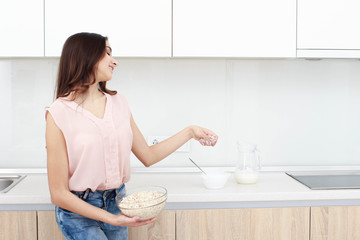 Serious attitude. Young smiling lady standing in a kitchen.