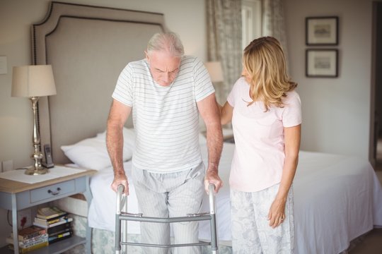 Senior Woman Helping Man To Walk With Walker