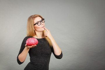 Woman thinking and holding fake brain