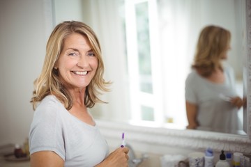 Portrait of senior woman holding toothbrush in bathroom