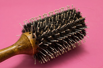 Dropped hair on a comb on a pink background, problems with hair.