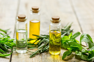 cosmetic oil in bottle with herbs on light table background