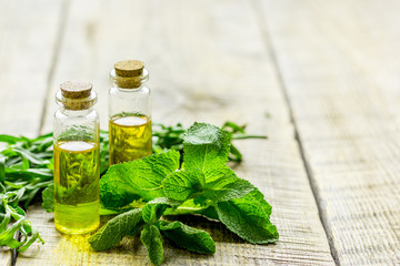 cosmetic oil in bottle with herbs on light table background