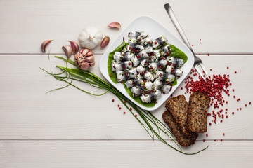 Baltic herring rolls in rose pepper and garlic marinade. With rye bread and ingredidients on white...