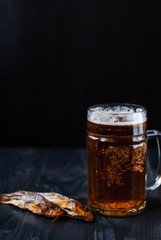 A glass of beer with dried fish. Light beer with sea Bullhead. Goby and beer on a dark background