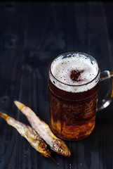 A glass of beer with dried fish. Light beer with sea Bullhead. Goby and beer on a dark background