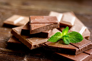 black and milk chocolate bars with mint dark wooden table background