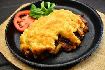 Chicken steak with fried cheese on top and salad on metal pan