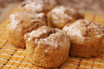 Tasty muffins with sugar powder on wooden mat