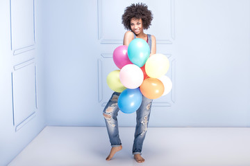 Happy young girl with afro holding balloons.