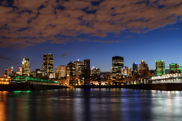 Montreal skyline with waterfront view.  Reflection of buildings on the water.  Streak of clouds.