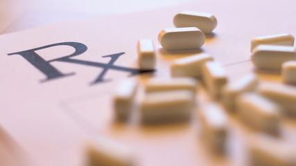 Prescribing, overprescribing prescription pills concept with blank RX form and falling tablets, close up in natural light, shallow DOF.