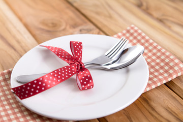 close up dinner setting fork and spoon on plate on wooden background