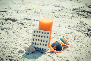 Medical pills, carrot juice and sunglasses at beach, concept of vitamin A and beautiful, lasting tan