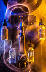 Electronic Cigarette, Vape with red smoke and liquid juice on a black and wooden background,...