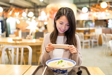 Woman taking photo on her noodles in restaurant