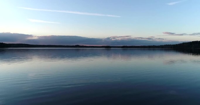 Lake bodom, Cinema 4k aerial rising view above mirroring bodom lake, on a sunny spring evening, in Espoo, Finland