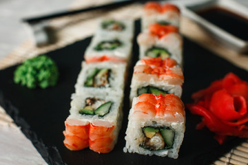 Set of fresh delicious sushi rolls with shrimps served on black slate closeup. Luxury Japanese restaurant menu photo.