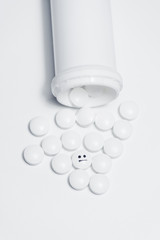 Pills pouring out of a white bottle
