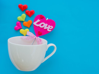White cup with colorful of heart on Valentine's Day love concept on blue sky background