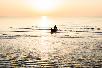 Obraz premium Silhouette of fishing boat and Beautiful tropical sunrise on the beach.