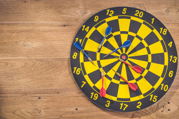 Dart arrow and dartboard on brown wooden background. Composition white free space for text or design