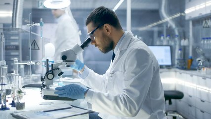 In a Modern Laboratory Research Scientist Experiments With Biological Materials, Uses Microscope and Writes Down Results. Shot on RED EPIC-W 8K Helium Cinema Camera. - Powered by Adobe