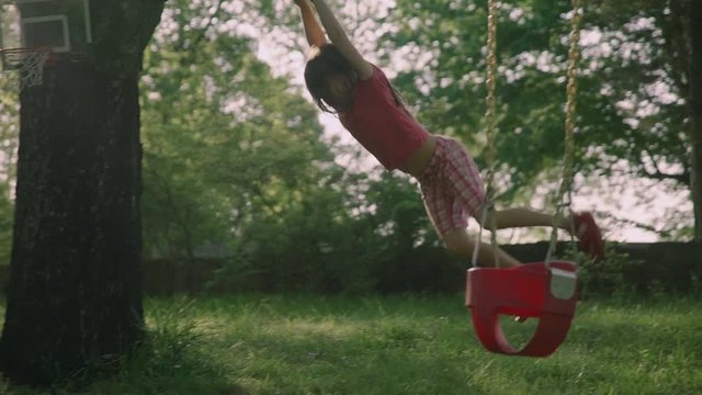 Little girl hang on sports rings at playground in house yard slowmotion 4k
