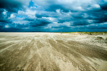 driftender sand im sturm bei dramatischem Himmel