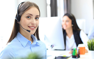 Smiling female call centre operator doing her job with a headset while looking at camera.