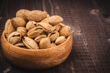 almonds in a wooden plate on a wooden table/almonds in a bowl on dark background