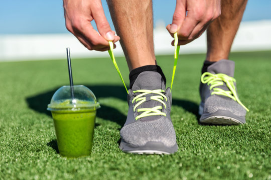 Green smoothie fitness man tying running shoes