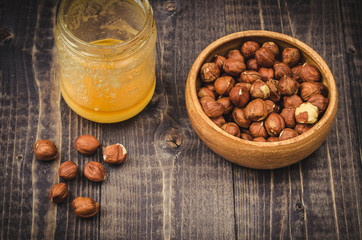 glass of honey and nuts in a wooden plate/honey and hazelnuts top view