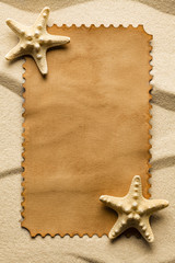 Blank paper label and starfish on beach sand
