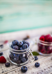 Tasty ripe and fresh forest blueberries in glass jar on wooden background. 