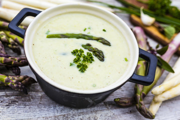 Delicious creamy asparagus soup on a wooden background.