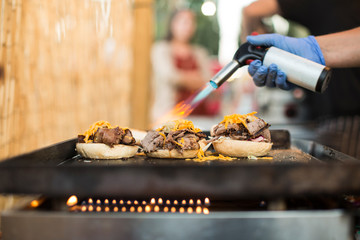 Chef using gas torch for cooking burgers