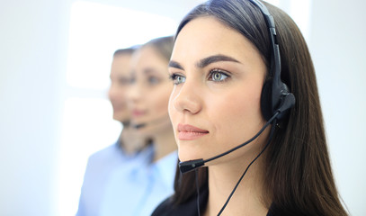 Portrait of call center worker accompanied by her team. Smiling customer support operator at work.