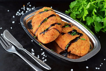Carrot fritters on a metal plate on a black abstract background. Healthy eating concept